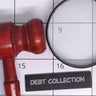 Debt collection concept with gavel and magnifying glass 