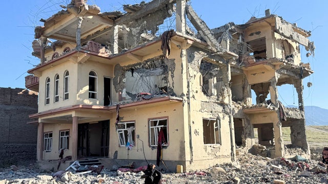 A man sits in front of a destroyed building after an attack, which the Taliban say was an airstrike carried out by Pakistan's security forces, in Samkani District 
