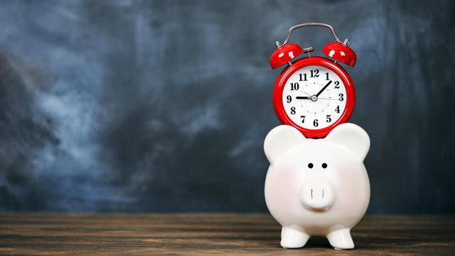 Bright red clock with piggy bank and chalkboard background 