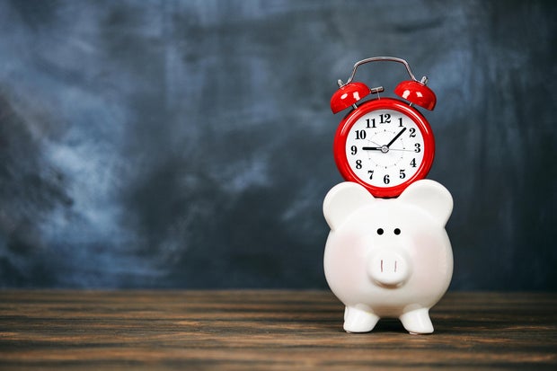Bright red clock with piggy bank and chalkboard background 