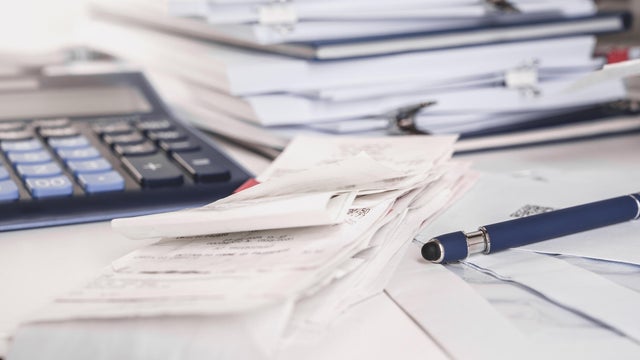 Stack of receipts with calculator. Lots of documents, papers and notepads on a desk. Taxes 