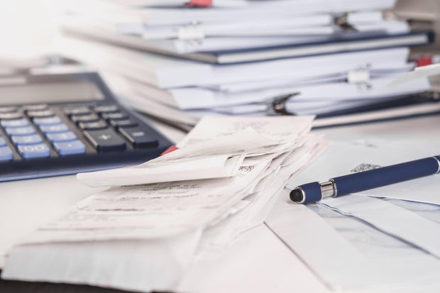 Stack of receipts with calculator. Lots of documents, papers and notepads on a desk. Taxes 