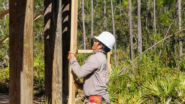 Side view of construction working holding wooden plank on job site 