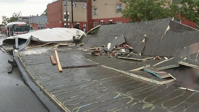 A large section of roof and piles of debris are seen on the ground near the building 