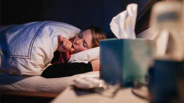 Woman coughing in bed. 