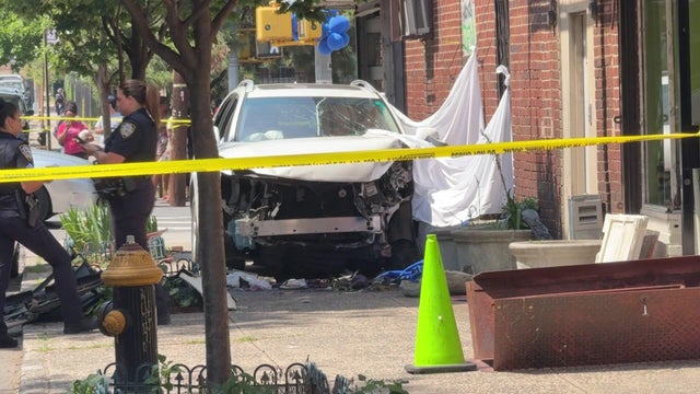 Car on sidewalk behind crime scene tape 