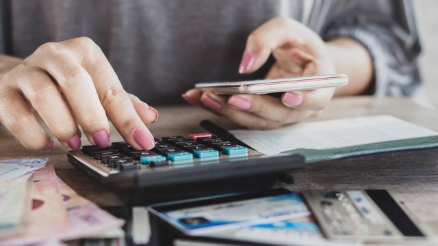 woman hand calculating her expenses and debt from credit cards with smart phone 