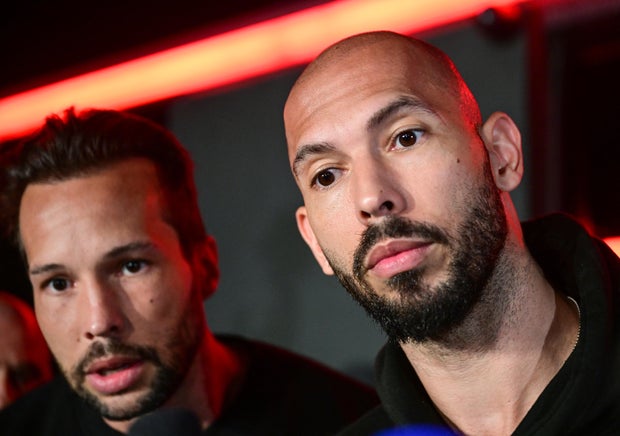 Andrew Tate, right, and his brother Tristan speak to the media as they arrive in Bucharest, Romania, March 22, 2025.
