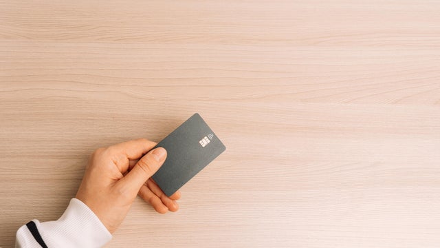 Hand Holding Contactless Card on Wooden Table 