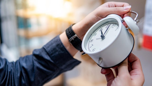 Male hand adjusting the time on white clock 