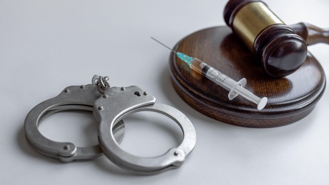 Syringe , gavel and handcuffs on table 