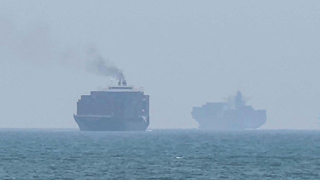 FILE PHOTO: A statue of Iranian military members stands as vessels in the Strait of Hormuz are visible near the beach of Bandar Abbas 