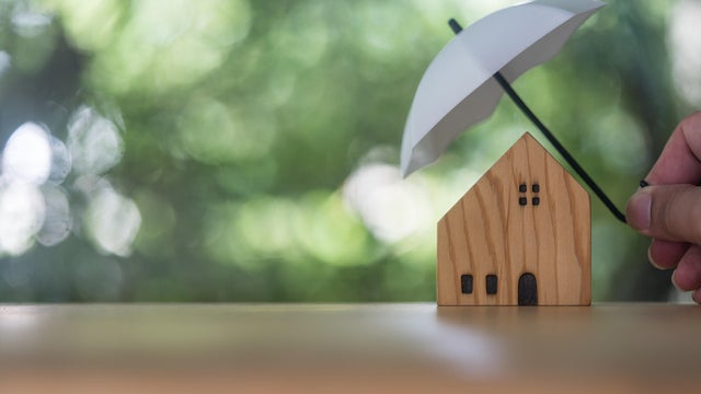 Home and real estate insurance ideas, Man use white small umbrellas and wood homes. 