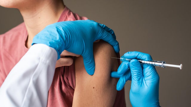 Close up of teen boy getting vaccinated by doctor holding a needle. 