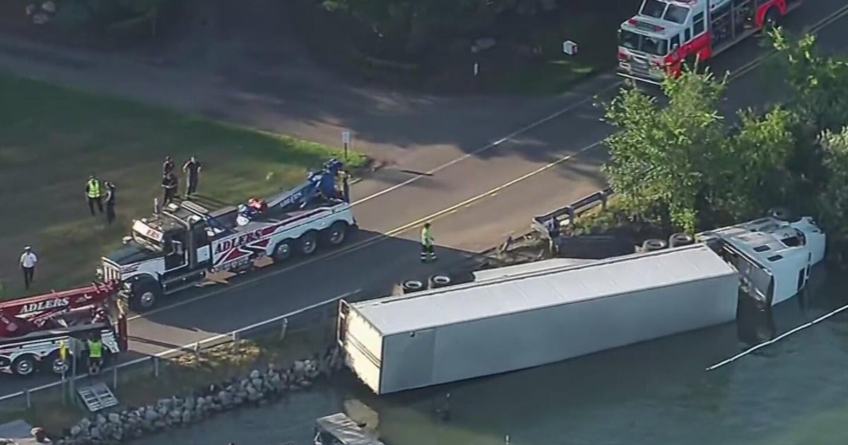 Authorities clean up fuel after semi-truck overturns into Oakland County lake