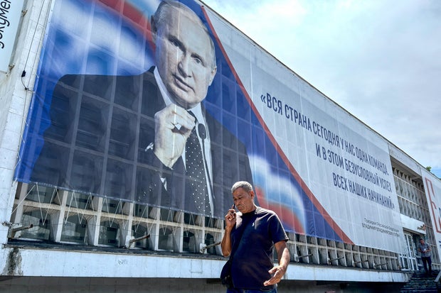 A man walks past a billboard displaying a portrait of Russia's President Vladimir Putin in Sevastopol, on the Russian-annexed peninsula of Crimea, on July 23, 2026. 