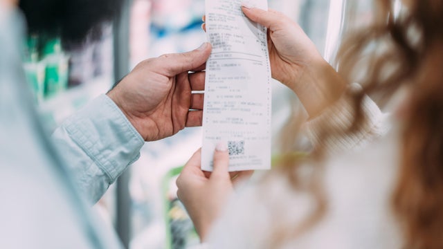 Couple shopping at a convenience store and checking the receipt. 
