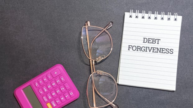 Debt forgiveness concept with calculator and glasses on desk