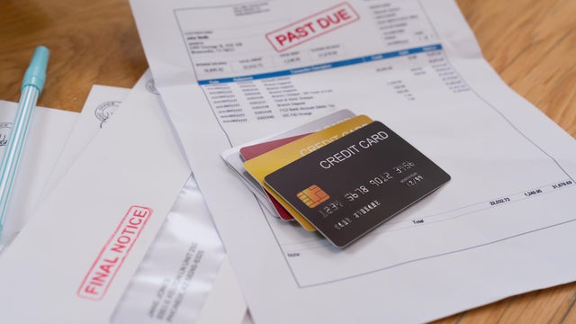 Stack of credit cards on top of an overdue statement of account with a red stamp payment past due notice. 