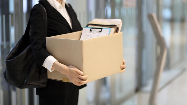 Businesswoman leaving office with box of personal items 