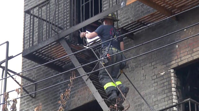 Firefighter climbs fire escape at fire-damaged building 