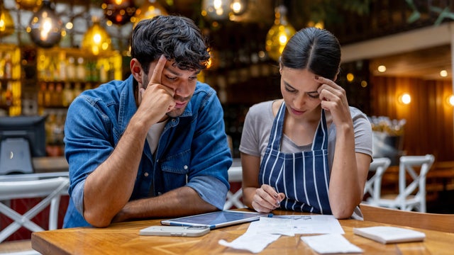 Owner and waitress doing the accountancy at a restaurant and looking worried 