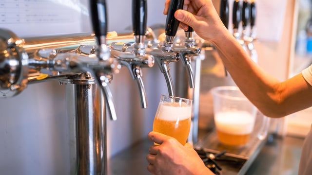 Female owner and young male brewer brewing beer in a microbrewery. 
