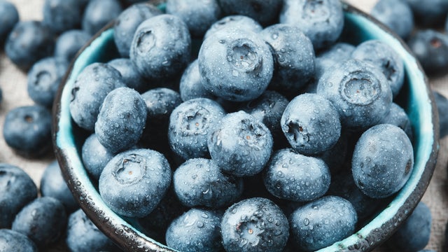 A young Asian woman is choosing blueberries in a supermarket 