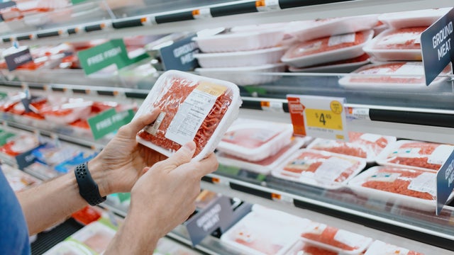 Man Checks Price of Ground Beef at Supermarket 
