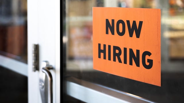 "now hiring" sign posted on business door 