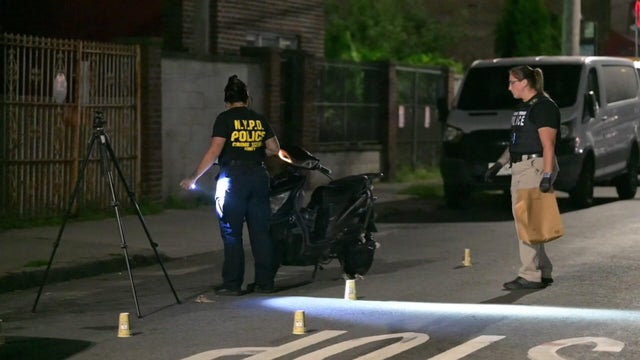 NYPD officers investigate scooter parked in street 