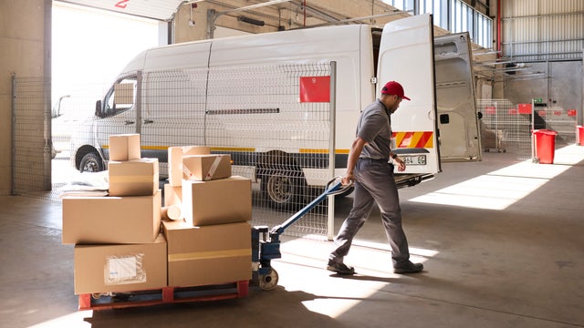 Delivery man pulling hand truck of cardboard boxes 