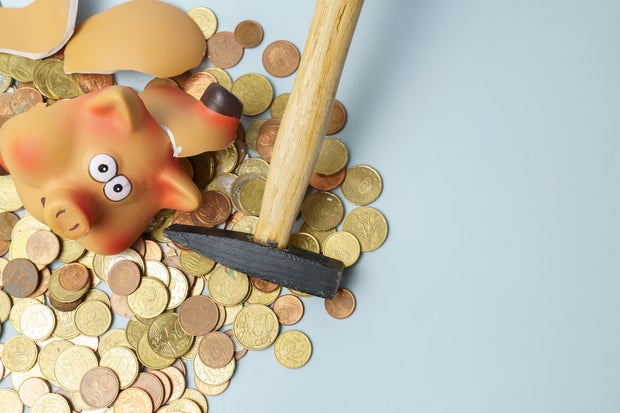 Breaking piggy bank with hammer extracting money