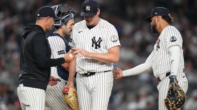 New York Yankees pitcher Brent Headrick, center, hands the ball to manager Aaron Boone, left, as he leaves during the eighth inning of a baseball game against the Houston Astros Tuesday, Aug. 25, 2026, in New York. 