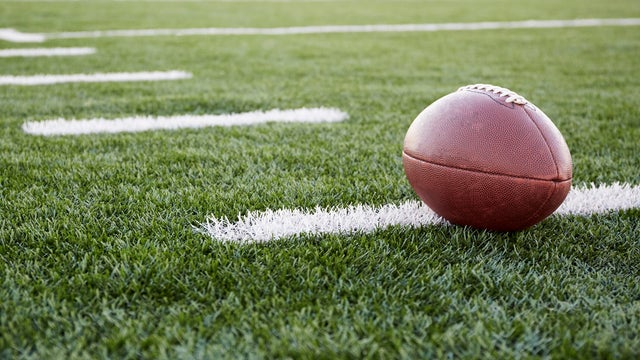 Close up of American football ball on green playing field 