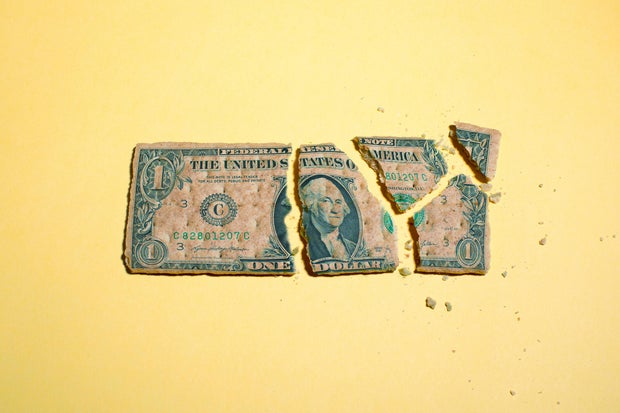 Dollar Bill Breaking Apart into Pieces on Yellow Background