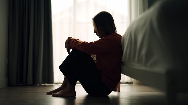 Side view of a woman sitting in her bedroom 