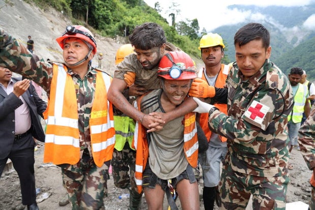 A man who survived is carried by members of a search and rescue team after being rescued from inside a tunnel at the Trishuli-3A Hydropower Project following devastating floods and mudslides that struck the Bhotekoshi River 