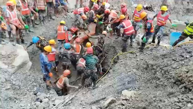 Rescuers carry a survivor from a tunnel linked to a hydropower station following deadly flash floods and mudslides, at this location given as Rasuwa district 