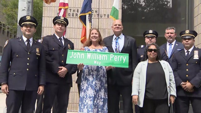Family members holding "John William Perry Way" street sign 