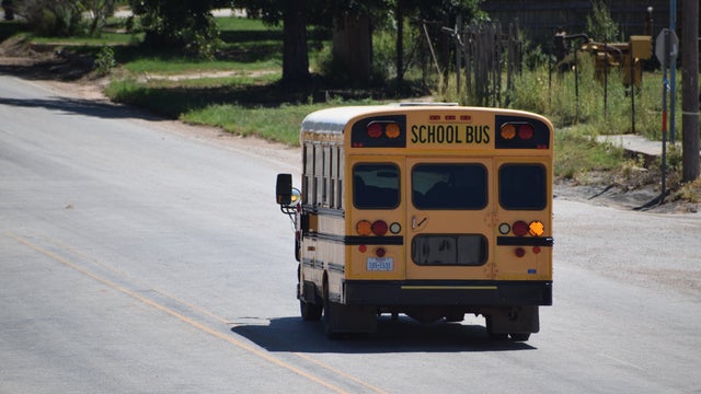 Short yellow school bus driving down a road in Rule Texas - August 2021 