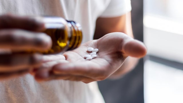 Young man spilling multiple pills in his hand. 