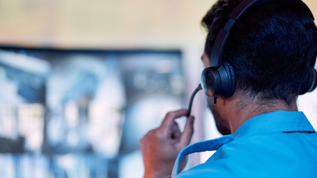 Police dispatch, communication headset and man talking, speaking and consulting with security, monitor CCTV or callcenter. Conversation, support consultation and back of person chat about 911 service 