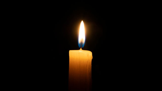 orange candle burns on a black background with a reflection copy space 