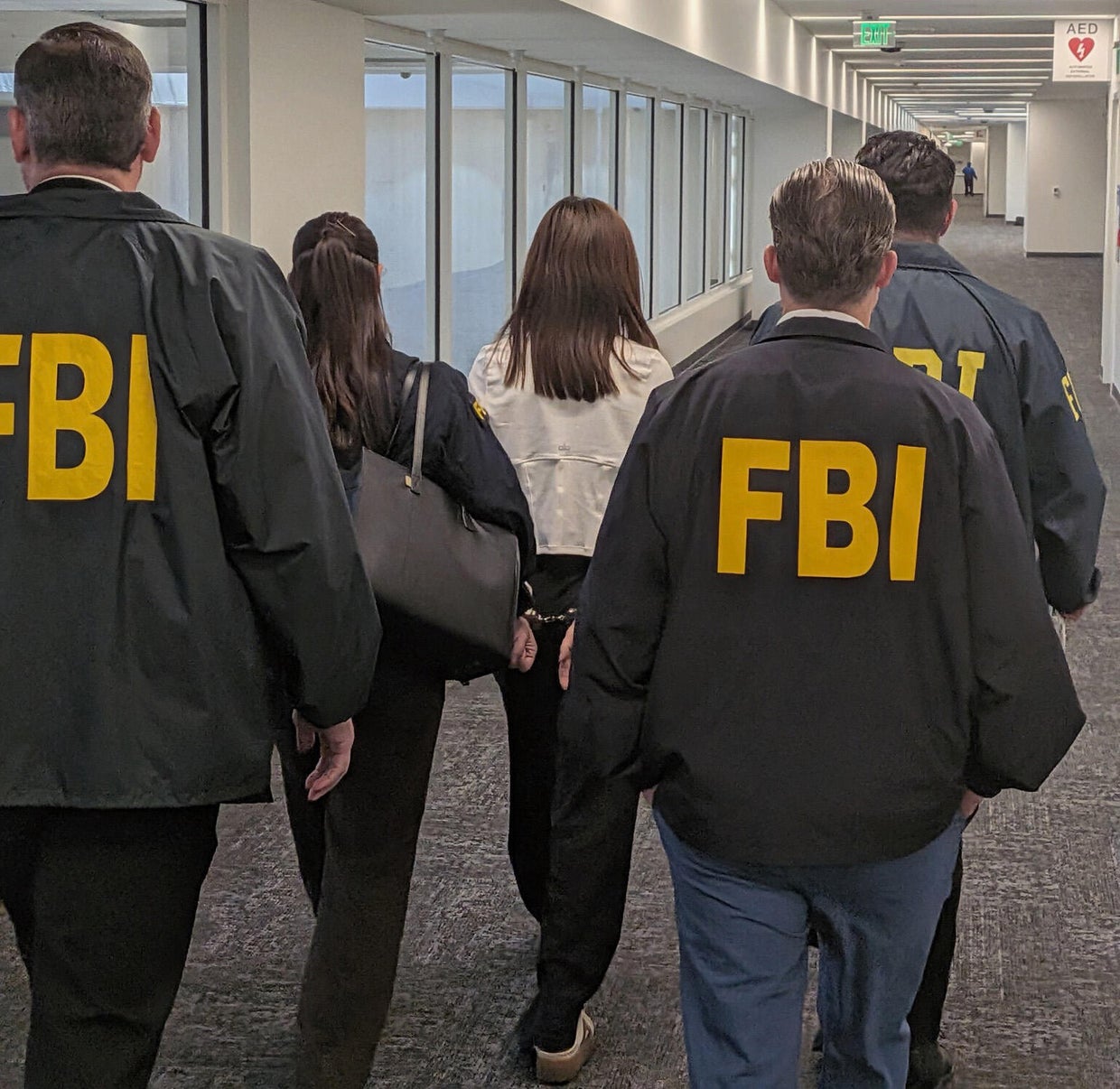 FBI agents walk with Wanying "Heather" Zhang in handcuffs after her arrest