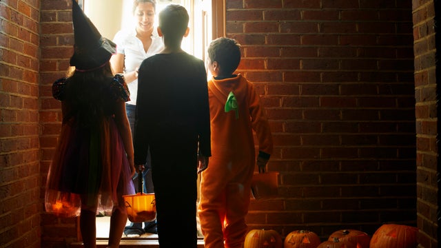 Rear view of three children wearing halloween costumes trick or treating 