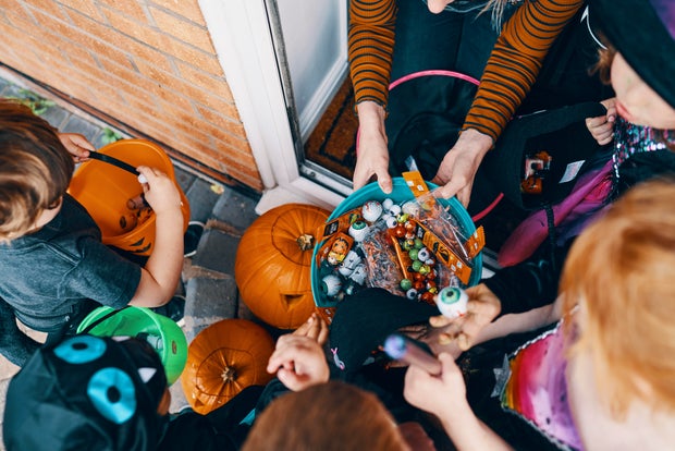 Overhead view of a group of children at a front door taking sweets from a bowl at Halloween.