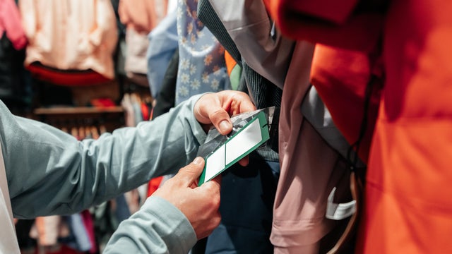 A man is examining a tag in a clothes store. 