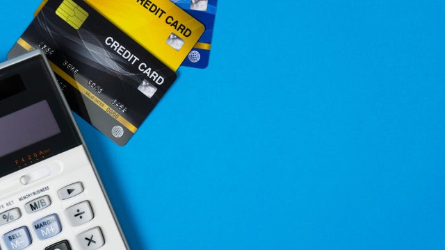 The concept of calculating debt and expenses at the end of the month. Online shopping concept. Credit card with calculator on blue background and space. Depicts expenses that need to be pay. 