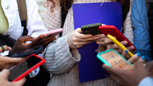 Close up of young college students hands holding mobile phones 